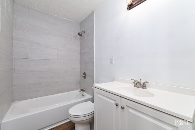 full bathroom featuring vanity, toilet, tiled shower / bath combo, and a textured ceiling