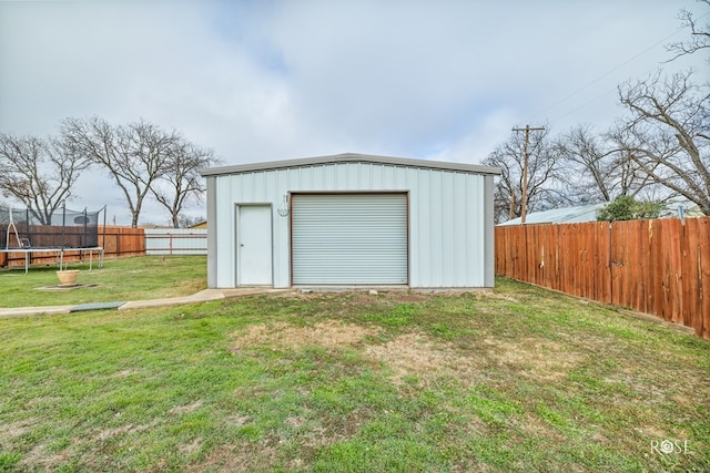 garage with a trampoline and a lawn