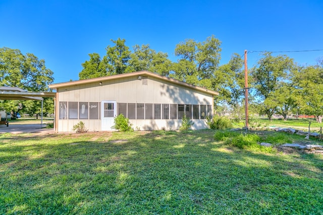 back of house featuring a sunroom and a lawn