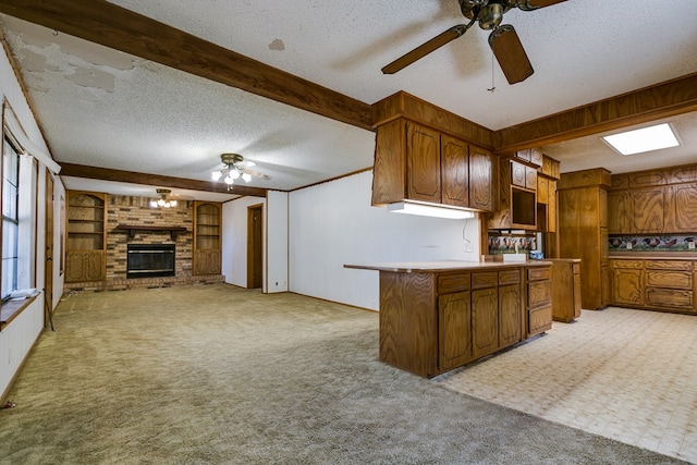 kitchen with a fireplace, ceiling fan, kitchen peninsula, light carpet, and a textured ceiling