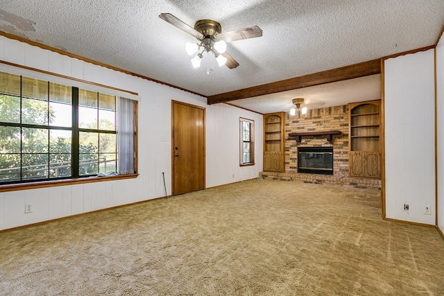 unfurnished living room featuring built in features, carpet flooring, a textured ceiling, a brick fireplace, and beamed ceiling