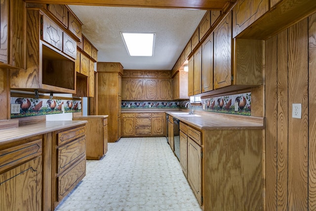 kitchen with sink, black dishwasher, and a textured ceiling