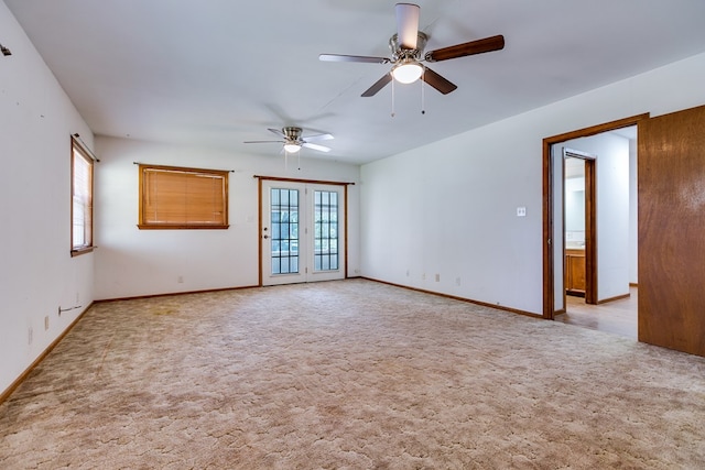 carpeted spare room featuring french doors, ceiling fan, and plenty of natural light