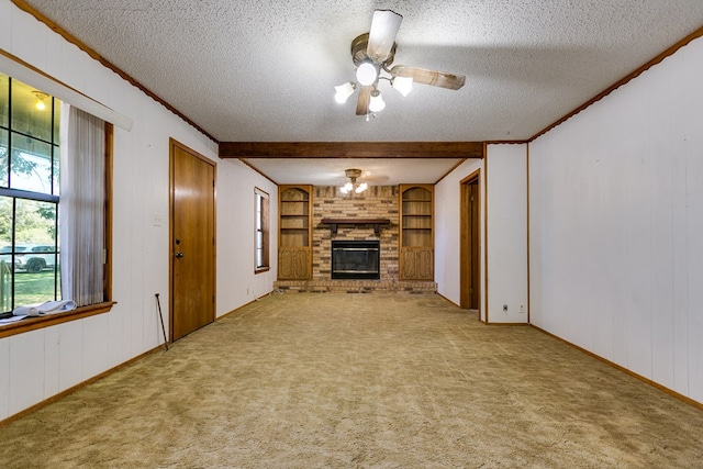 unfurnished living room with built in features, ceiling fan, a fireplace, a textured ceiling, and light colored carpet