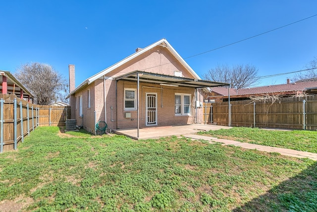 rear view of house with central air condition unit, brick siding, a fenced backyard, and a patio area