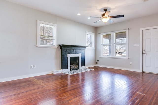 unfurnished living room featuring hardwood / wood-style floors, recessed lighting, a premium fireplace, baseboards, and ceiling fan