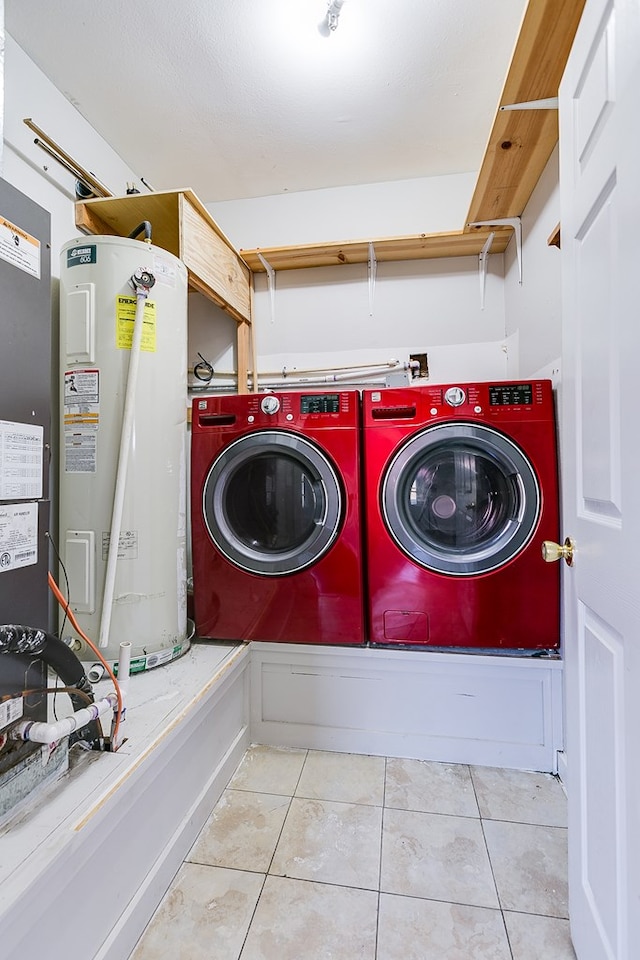 clothes washing area featuring electric water heater, washing machine and dryer, laundry area, and tile patterned flooring