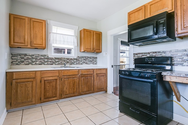 kitchen featuring a sink, plenty of natural light, black appliances, and light countertops