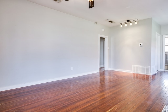 empty room with a ceiling fan, hardwood / wood-style flooring, baseboards, and visible vents