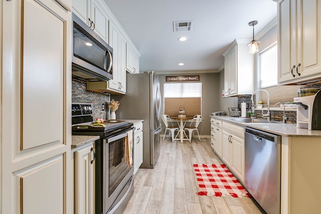 kitchen featuring pendant lighting, sink, appliances with stainless steel finishes, white cabinetry, and light wood-type flooring