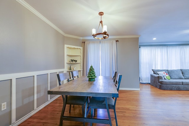 dining space featuring ornamental molding, hardwood / wood-style floors, an inviting chandelier, and built in shelves