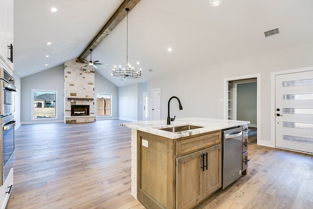 kitchen featuring appliances with stainless steel finishes, sink, hanging light fixtures, a center island with sink, and beam ceiling