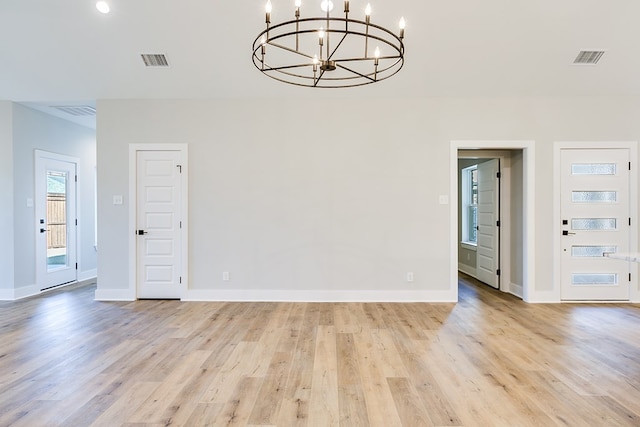 empty room featuring an inviting chandelier and light wood-type flooring