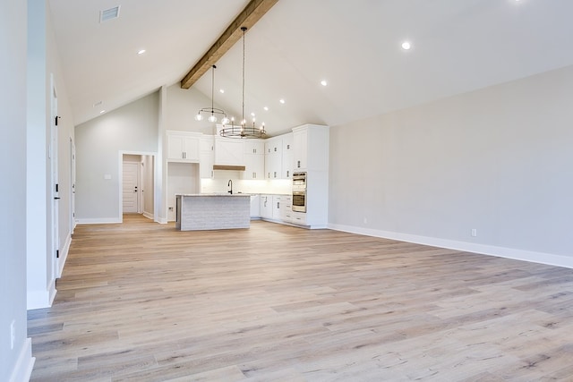 unfurnished living room featuring high vaulted ceiling, sink, light wood-type flooring, a notable chandelier, and beam ceiling