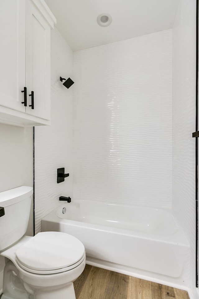 bathroom featuring hardwood / wood-style flooring, shower / tub combination, and toilet