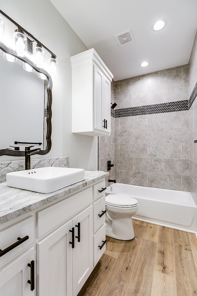 full bathroom with tiled shower / bath, vanity, and toilet