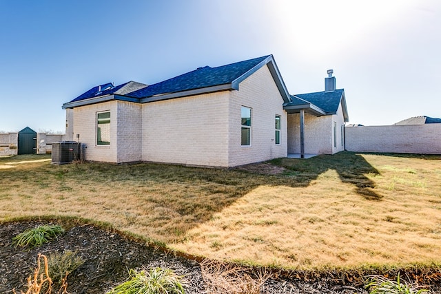 back of house with cooling unit and a lawn