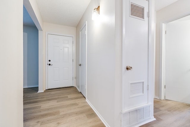 1809 N Harrison St, San Angelo, TX 76901 - corridor featuring baseboards, visible vents, light wood-type flooring, and a textured ceiling