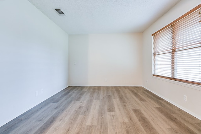1809 N Harrison St, San Angelo, TX 76901 - unfurnished room featuring light wood-style floors, visible vents, baseboards, and a textured ceiling