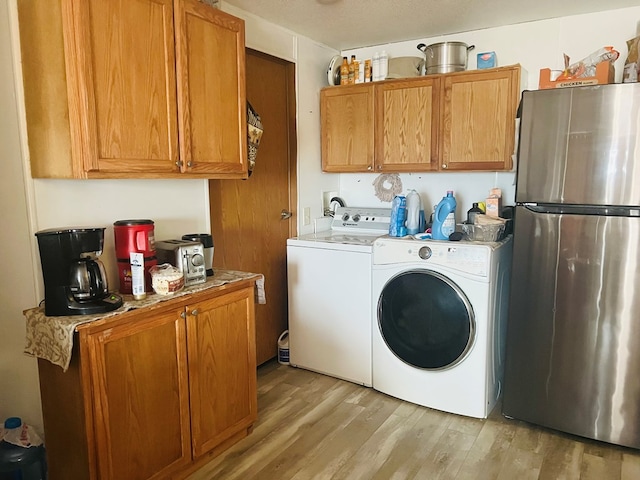 laundry room with washing machine and dryer and light wood-type flooring