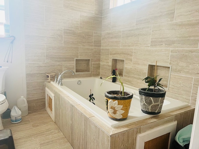 bathroom with tile walls, tiled tub, tile patterned floors, and toilet