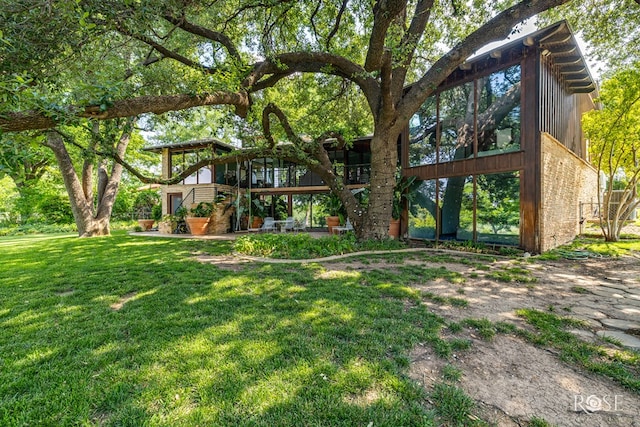 1703 Christoval Rd, San Angelo, TX 76903 - rear view of house with a sunroom and a lawn