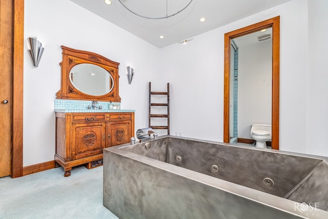 1703 Christoval Rd, San Angelo, TX 76903 - full bath with toilet, vanity, a jetted tub, recessed lighting, and baseboards