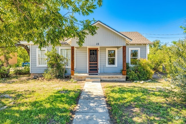 bungalow featuring a front yard, a shingled roof, and covered porch