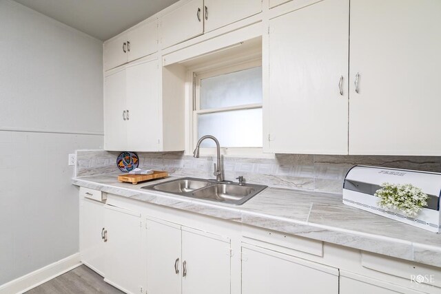 kitchen featuring a sink, white cabinets, and light countertops
