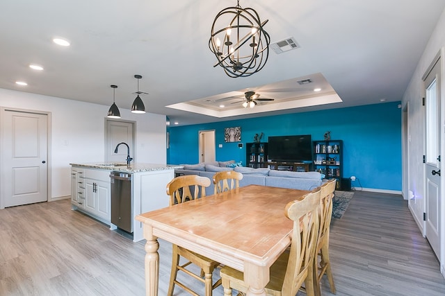 1501 Montague Ave, San Angelo, TX 76905 - dining space with light wood-type flooring, a raised ceiling, a ceiling fan, recessed lighting, and a chandelier