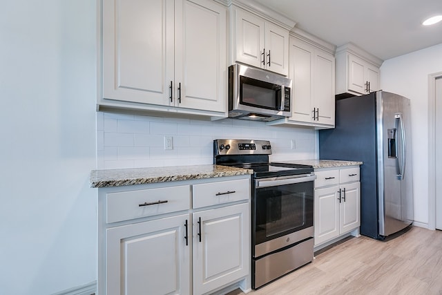 1501 Montague Ave, San Angelo, TX 76905 - kitchen featuring appliances with stainless steel finishes, tasteful backsplash, light wood finished floors, and white cabinets