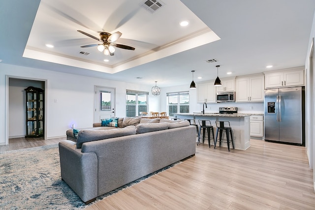 1501 Montague Ave, San Angelo, TX 76905 - living area with a tray ceiling, a ceiling fan, recessed lighting, light wood-style floors, and ornamental molding