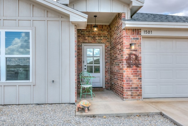 1501 Montague Ave, San Angelo, TX 76905 - property entrance with board and batten siding, brick siding, a garage, driveway, and roof with shingles