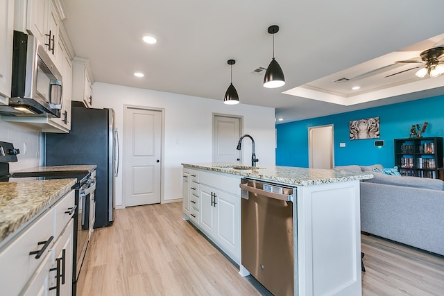 1501 Montague Ave, San Angelo, TX 76905 - kitchen featuring appliances with stainless steel finishes, open floor plan, light wood-style flooring, white cabinetry, and recessed lighting