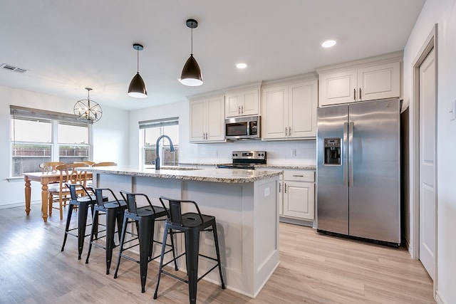 1501 Montague Ave, San Angelo, TX 76905 - kitchen with stainless steel appliances, light wood-style floors, light stone countertops, decorative backsplash, and a breakfast bar