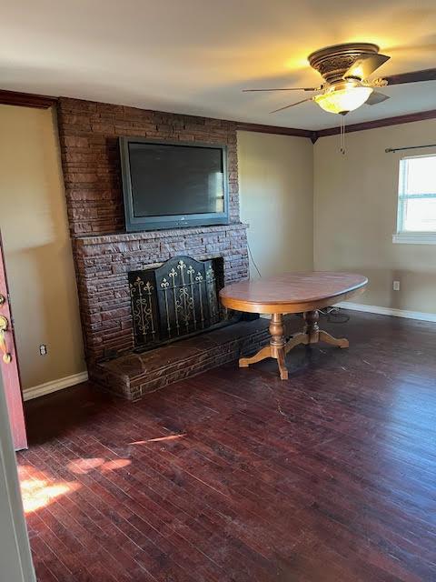 dining area with dark hardwood / wood-style flooring, crown molding, a fireplace, and ceiling fan