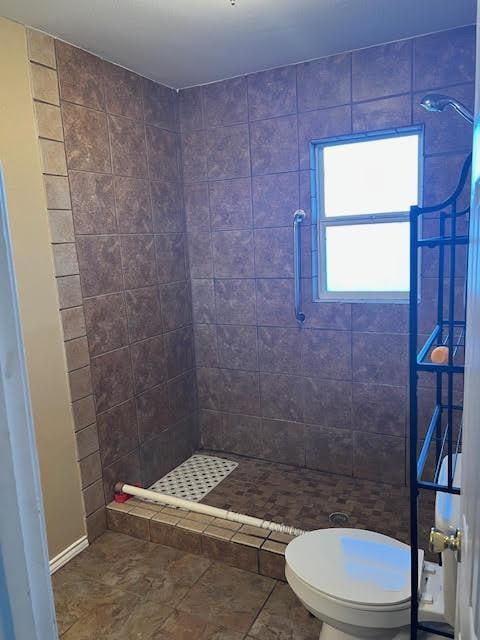 bathroom with a tile shower and toilet