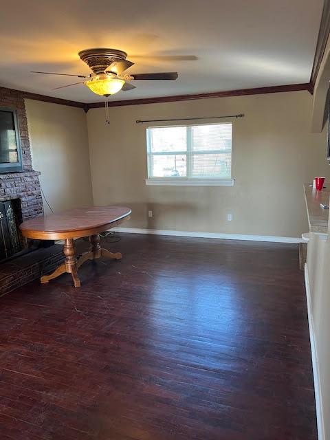 dining room with crown molding, dark hardwood / wood-style floors, a fireplace, and ceiling fan