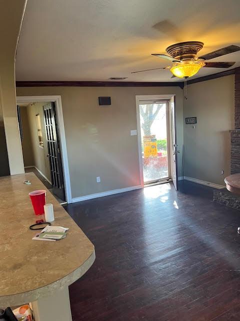 interior space featuring crown molding, dark wood-type flooring, and ceiling fan