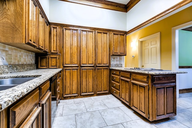 kitchen with light stone counters, ornamental molding, sink, and backsplash