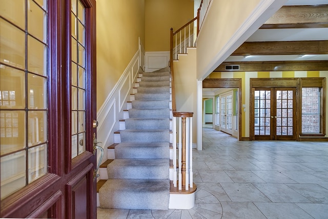 staircase with french doors and beamed ceiling