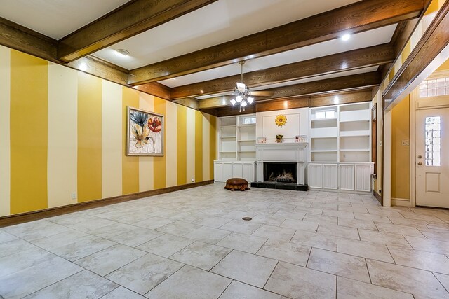 unfurnished living room with ceiling fan, beam ceiling, and built in shelves