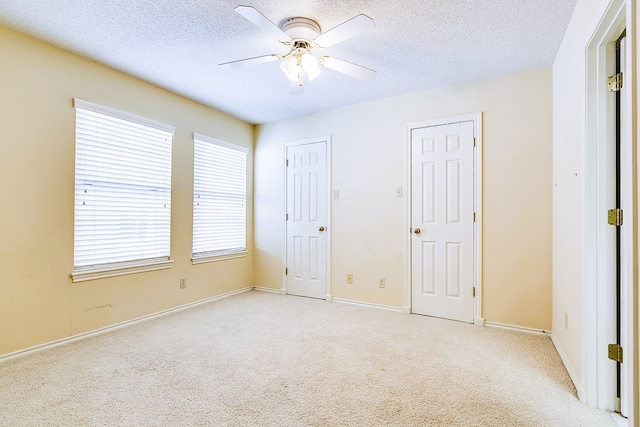 unfurnished bedroom with light colored carpet, a textured ceiling, and ceiling fan