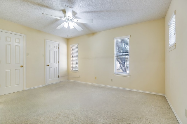 carpeted spare room featuring a textured ceiling and ceiling fan