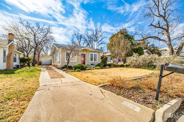 view of front of house with a garage, an outbuilding, central AC, and a front lawn