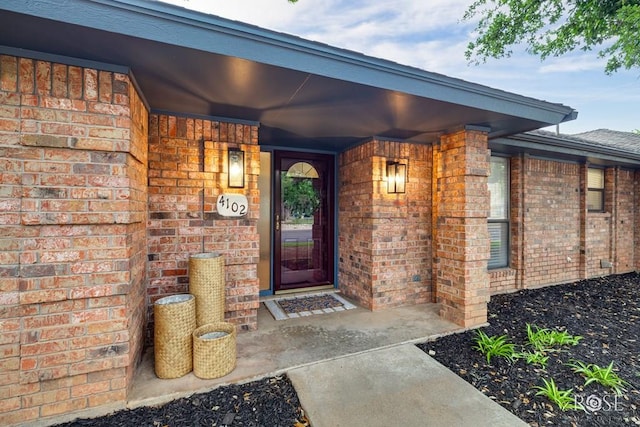 doorway to property with brick siding and a porch