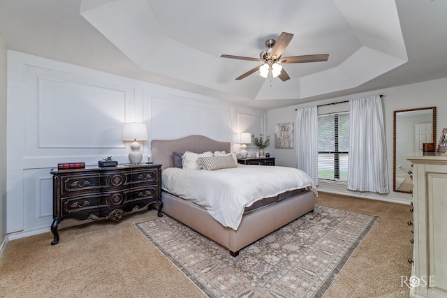 bedroom with a raised ceiling, carpet floors, and ceiling fan