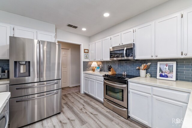 kitchen with appliances with stainless steel finishes, light countertops, white cabinets, and recessed lighting