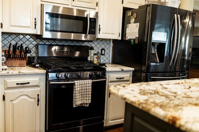 kitchen with white cabinetry, gas range oven, black refrigerator with ice dispenser, and backsplash