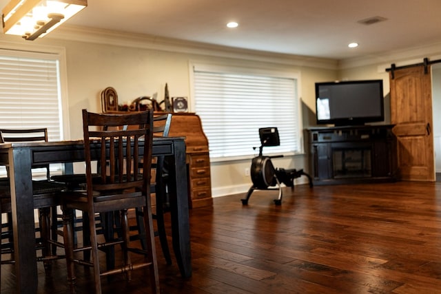 dining space with dark hardwood / wood-style floors, a barn door, and crown molding